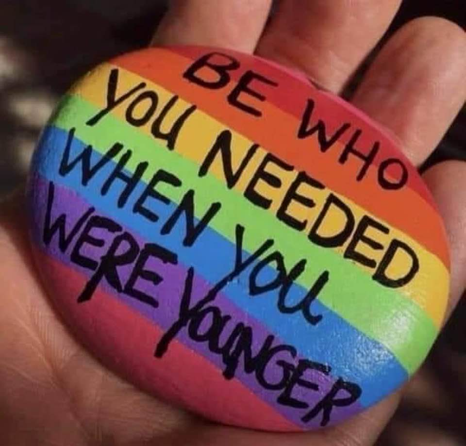 Be who you needed when you were younger, inscribed on a rainbow-colored rock